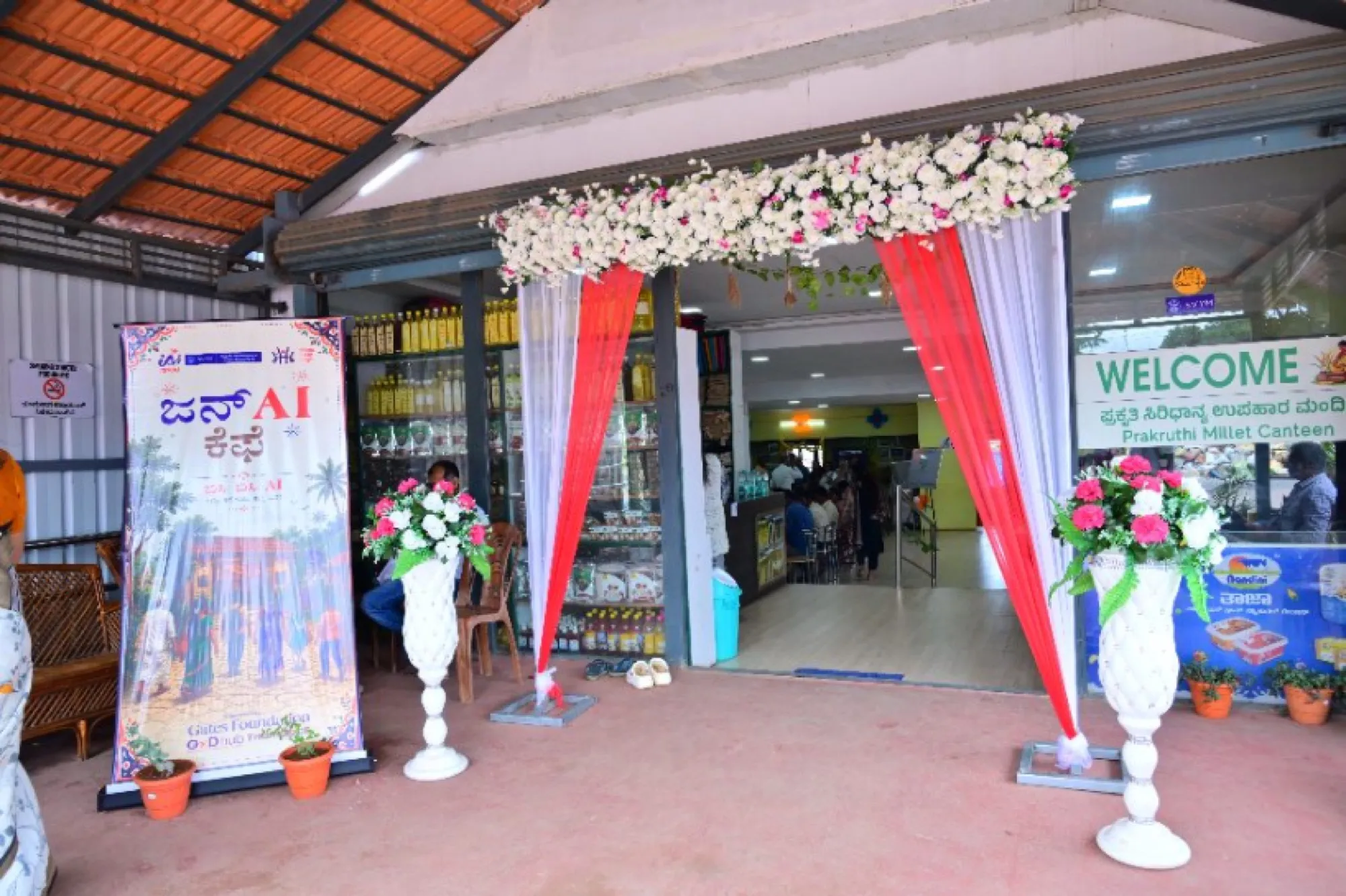 The decorated entrance of a JanAI Cafe with a welcome sign and flowers