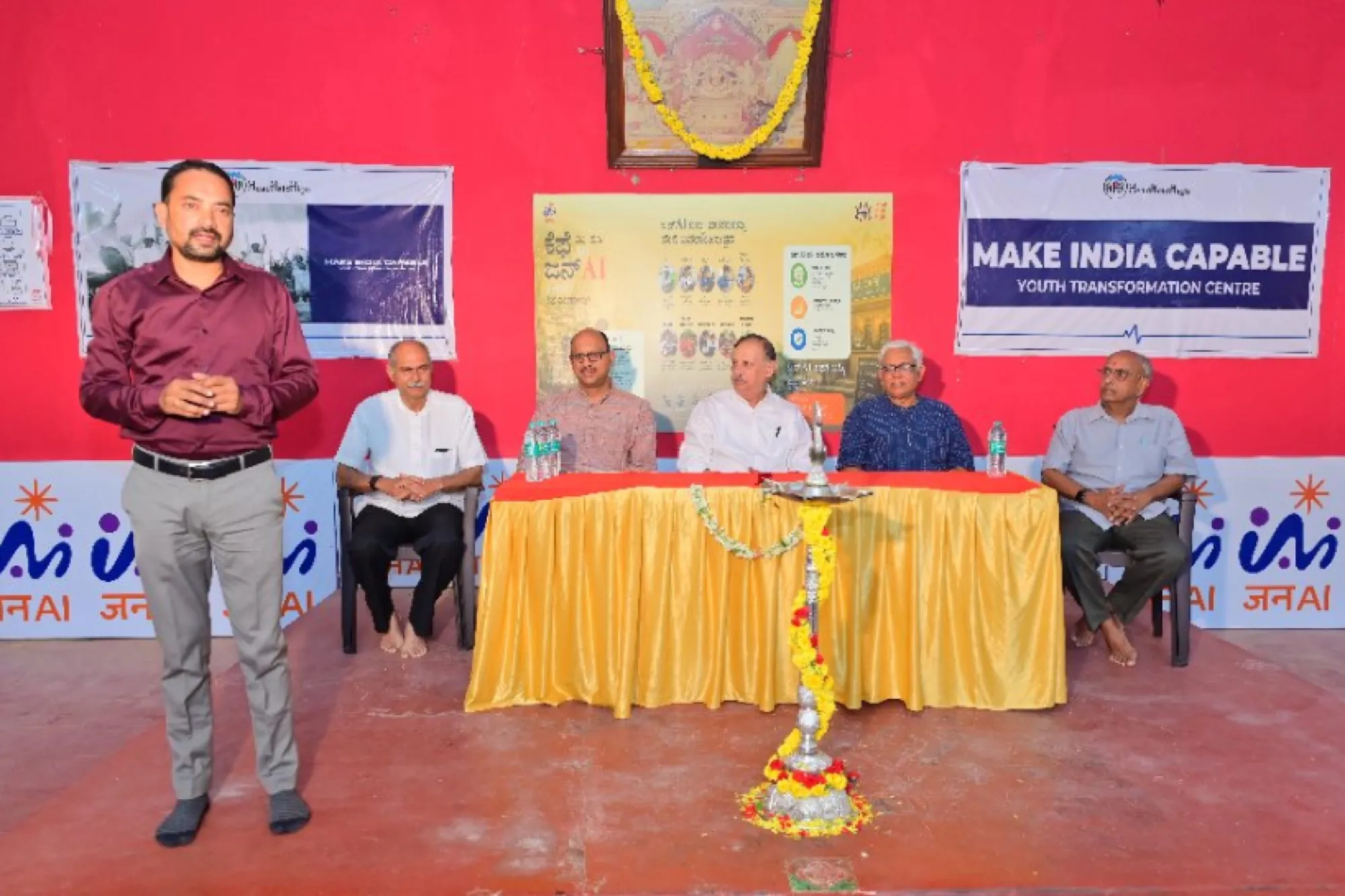 A speaker addresses guests seated at a table during a JanAI Cafe launch event
